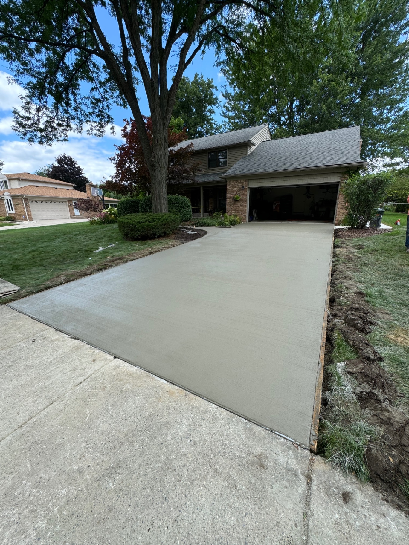 Newly poured broom-finished concrete driveway leading to an attached garage at a Southeast Michigan home