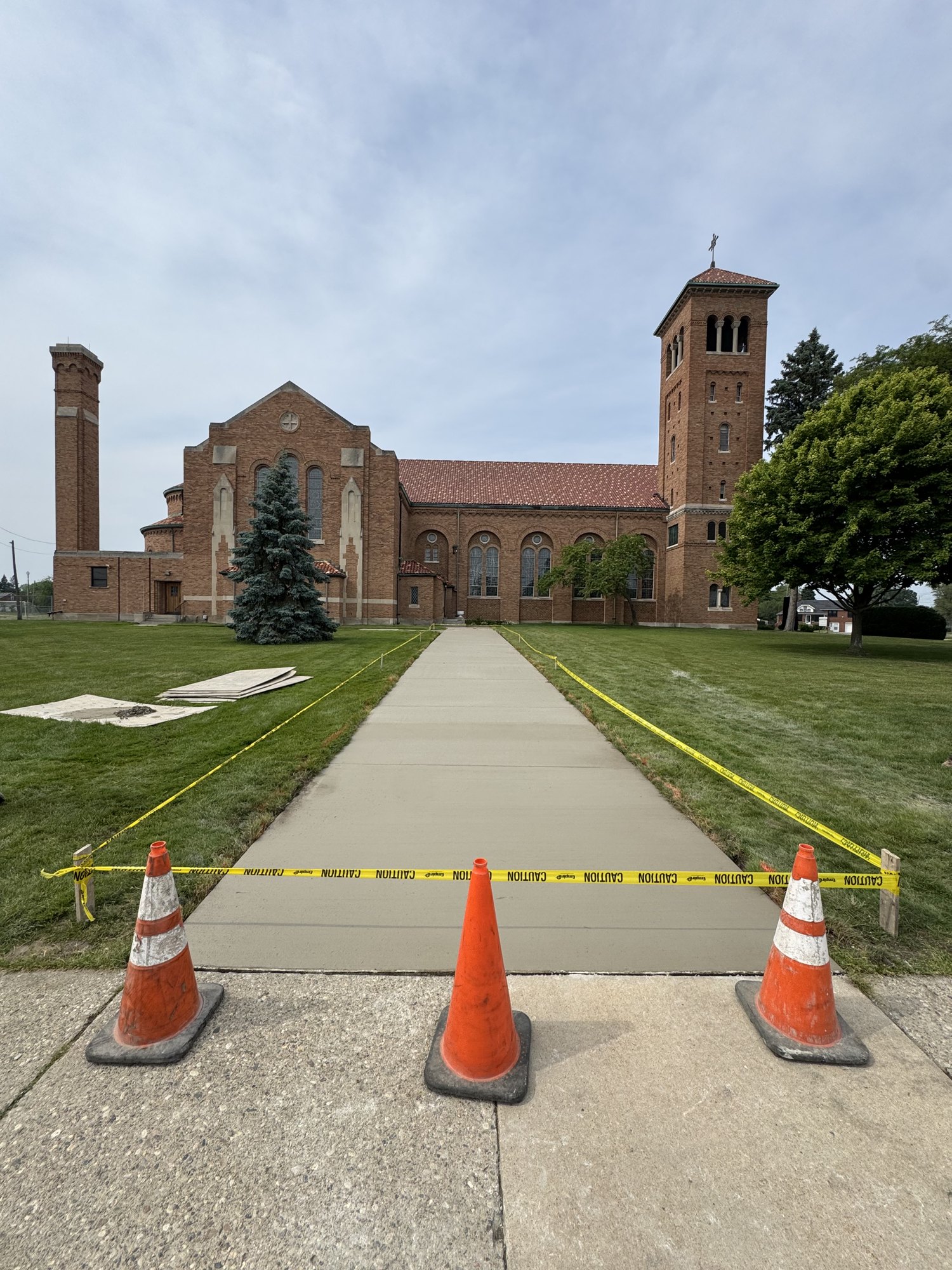 Completed broom-finished concrete entry walkway leading to a brick church entrance