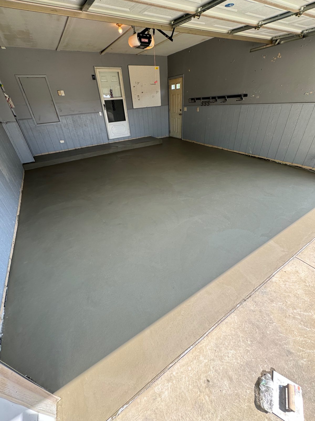 New smooth-troweled concrete garage floor with a fresh concrete apron at the overhead door